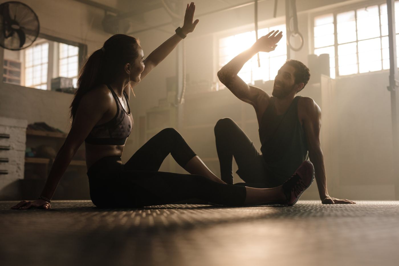 Two people high-fiving on a gym floor after a workout